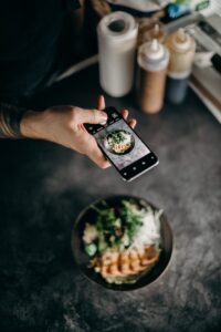 Influencer holds phone over ramen meal at restaurant.
